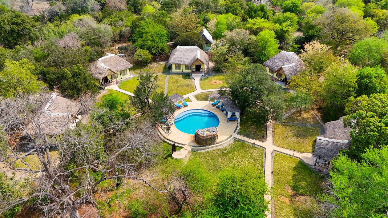 Die strohgedeckten Bandas der Africa Safari Selous umgeben einen Pool in der Wildnis von Nyerere.