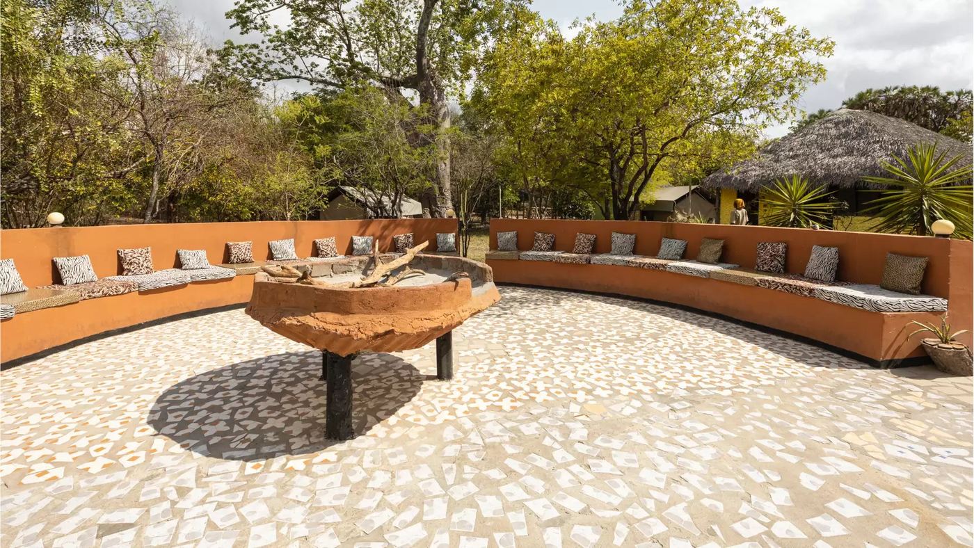 Zebra-gemusterte Kissen säumen eine gekrümmte Feuerstelle-Lounge in der Africa Safari Selous.