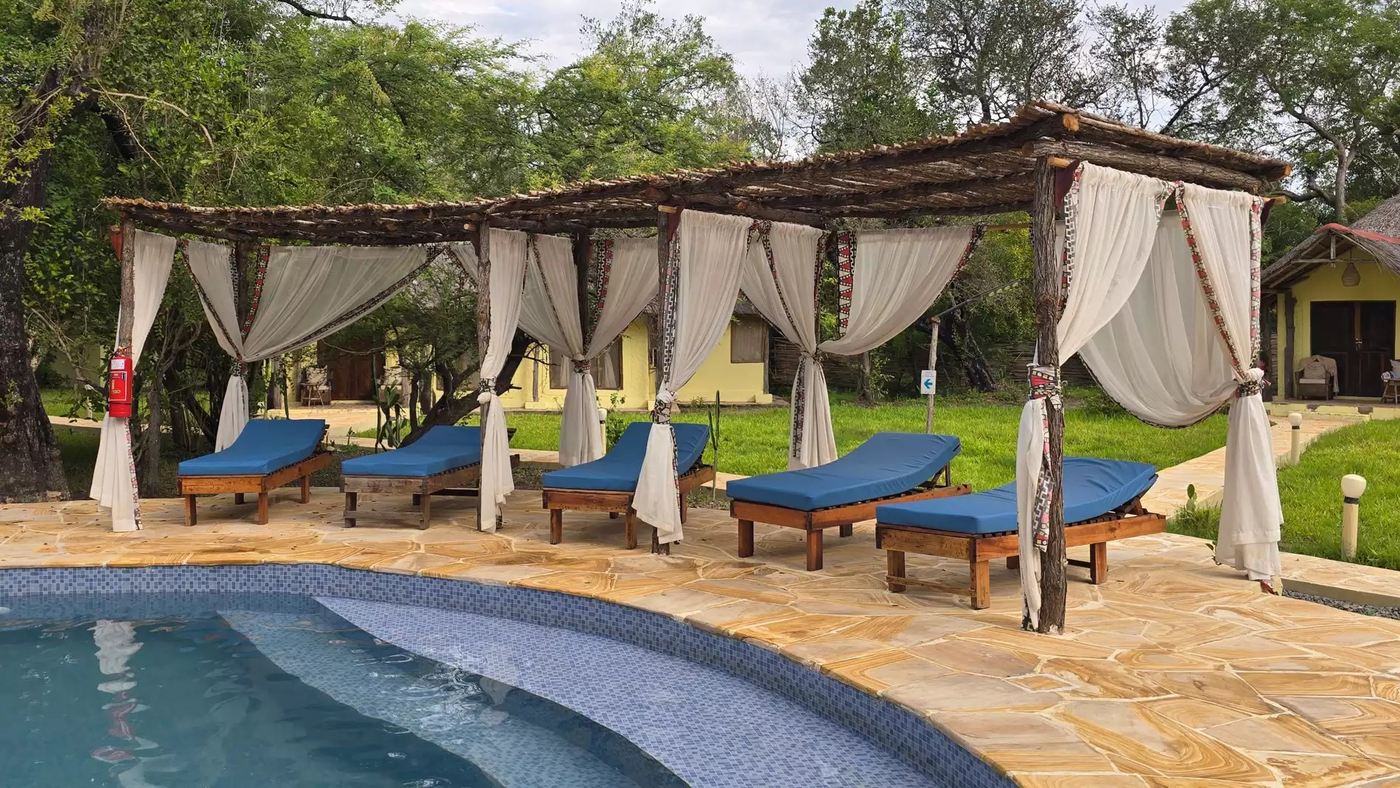 Drapierte Cabanas beschatten Liegestühle neben dem Pool in der Africa Safari Selous.