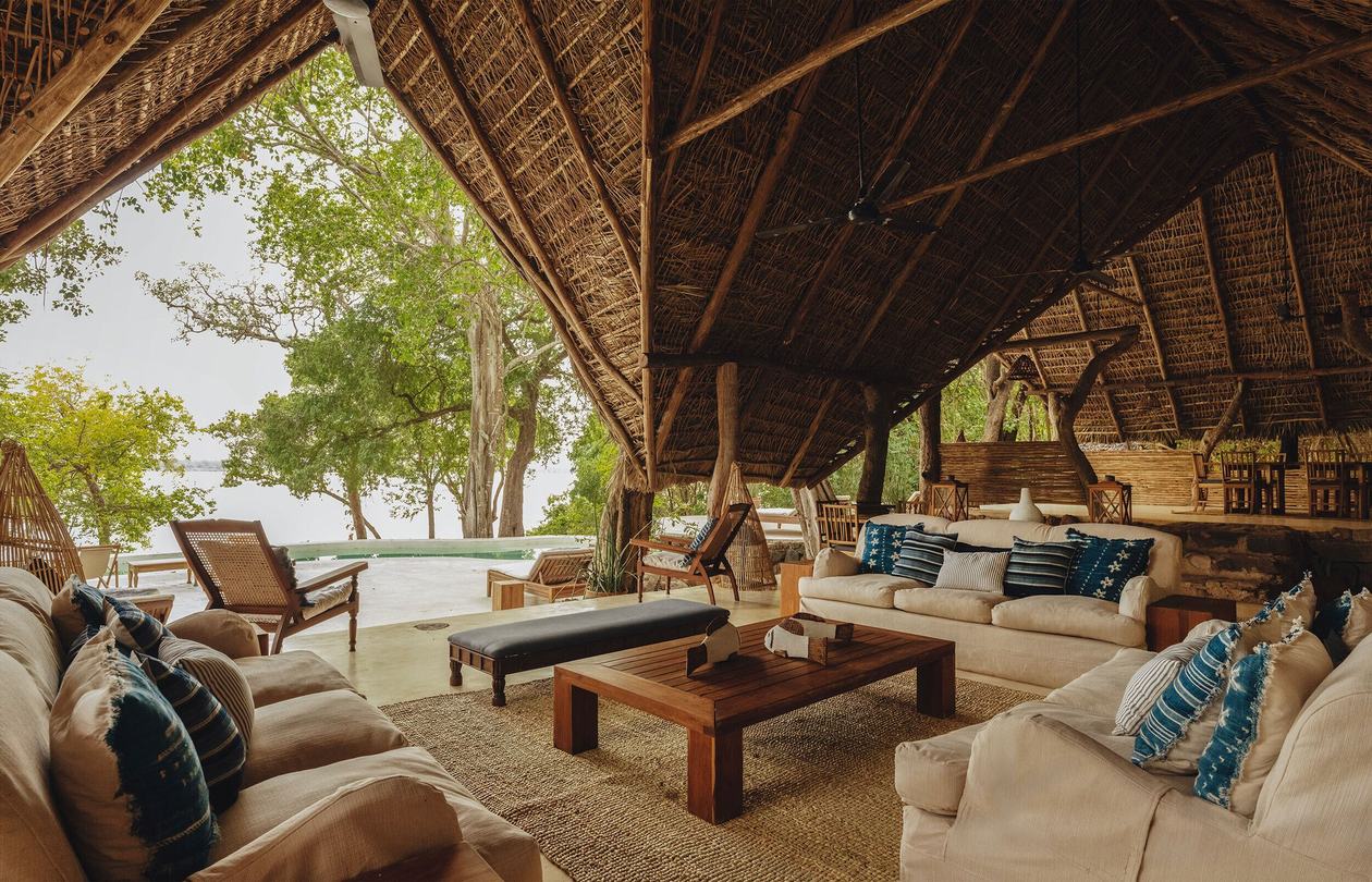 Cremefarbene Sofas blicken auf den Rufiji unterhalb von Kiba Points Strohdach-Lounge.