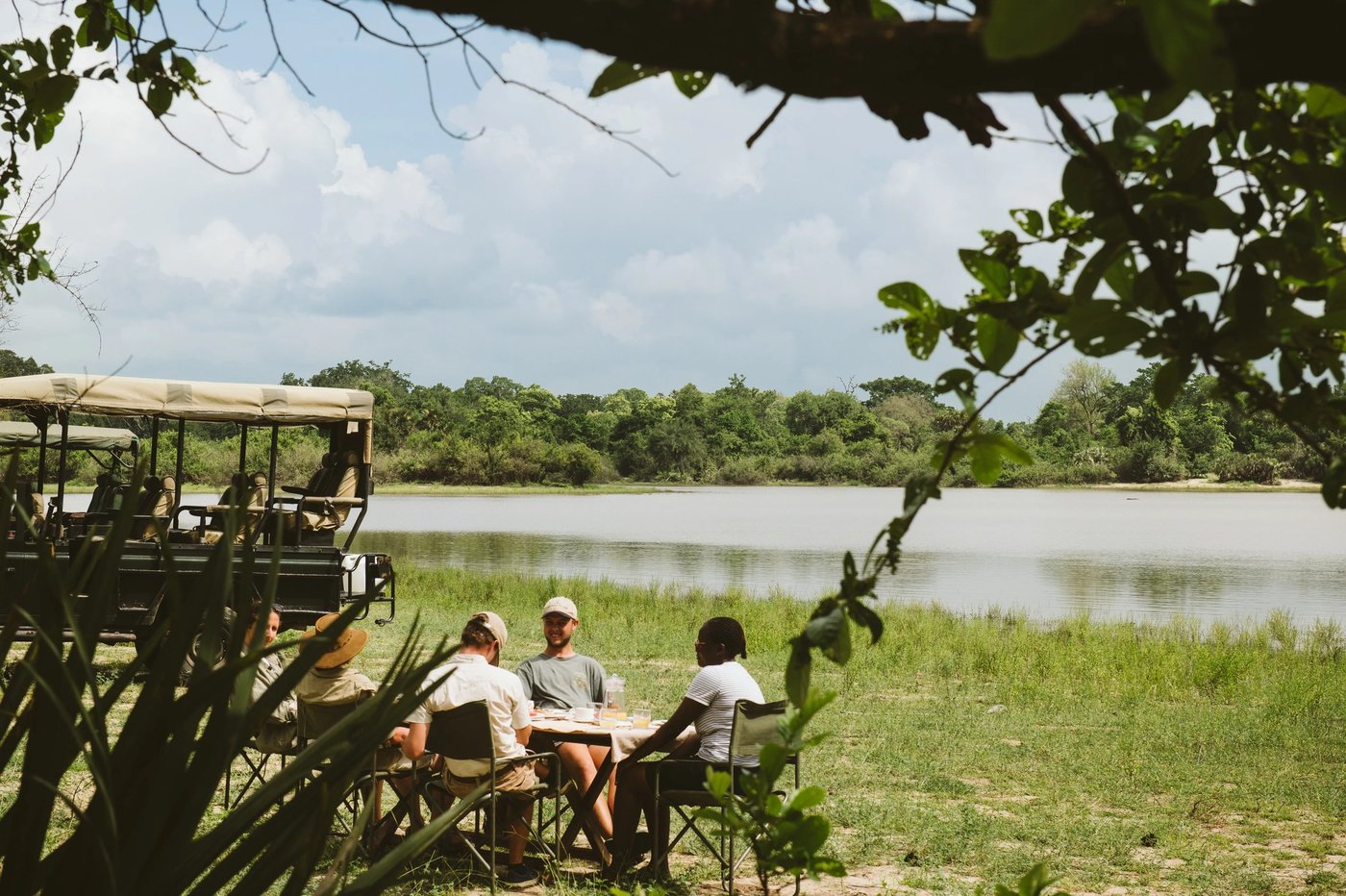 Gäste auf einem Pirschfahrzeug neben dem Fluss beim Rufiji River Camp