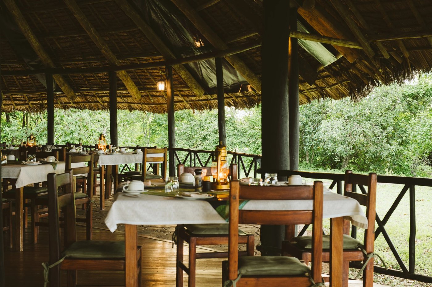 Esstische unter einem strohgedeckten Pavillon mit Blick auf Grünflächen im Rufiji River Camp aufgestellt.