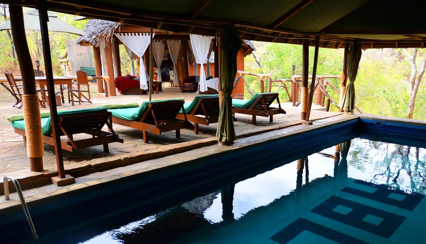 Zonnebedden staan langs een plensbad onder het riet van Sable Mountain Lodge.