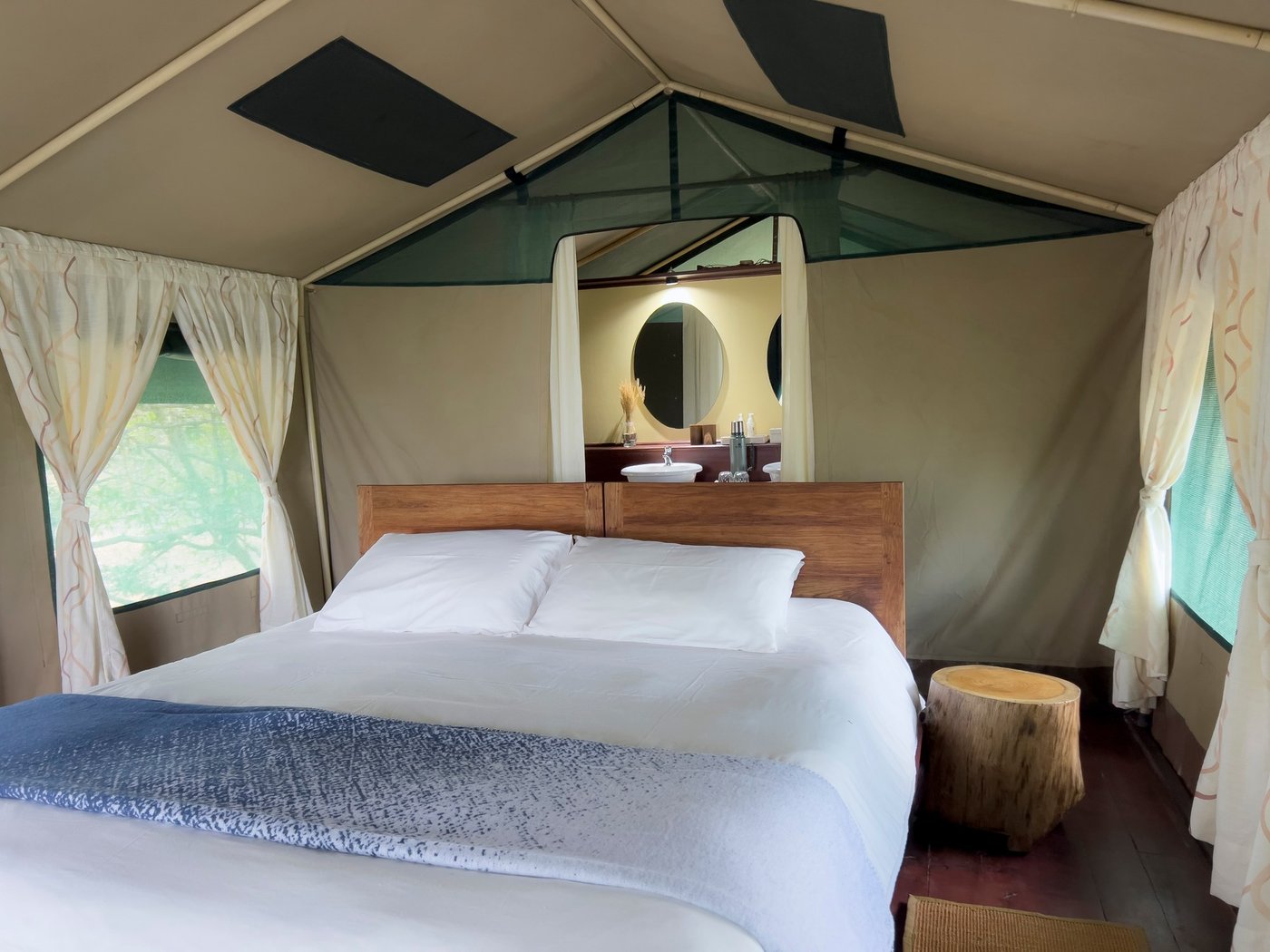 Zeltschlafzimmer mit Doppelbett und Ankleidepiegel im Selous Impala Camp