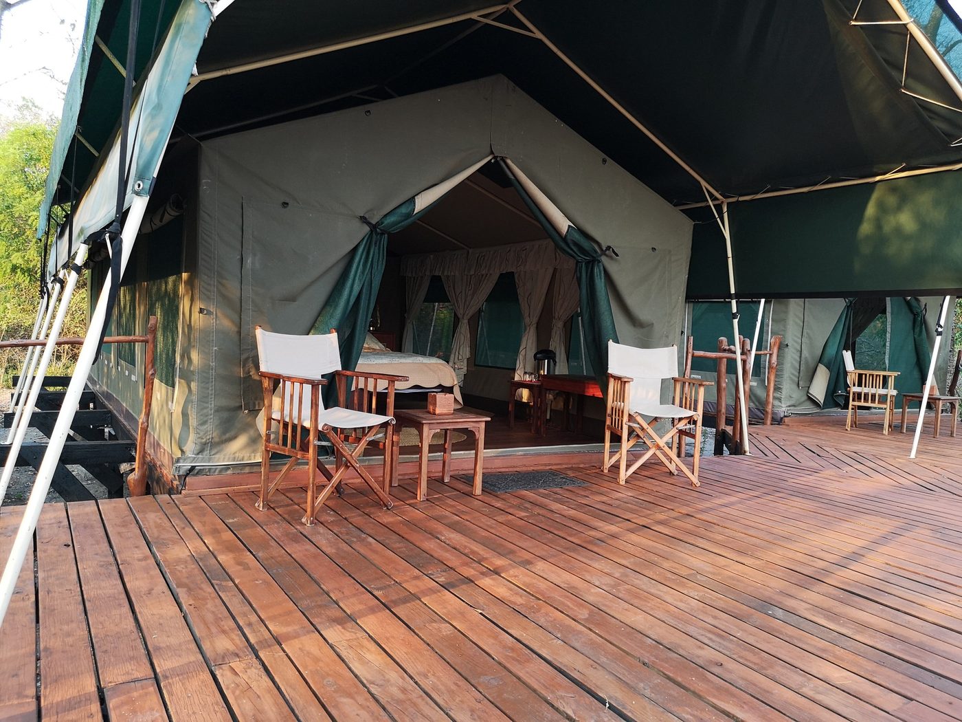 Holzplattform mit Campstühlen vor einem Gastzelt im Selous Impala Camp