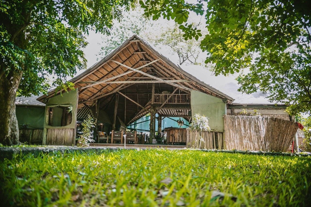 Strohdachgedecktes Lodgegebäude von oben mit grünem Ufergarten der Selous Kinga Lodge, Nyerere