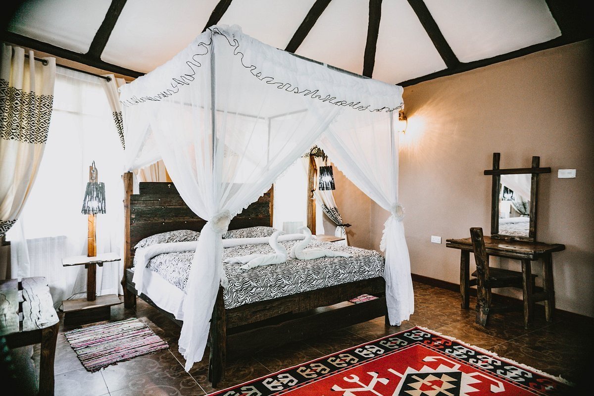Bett mit vier Pfosten unter einem weißen Baldachin in einem Gastzimmer der Selous Kinga Lodge