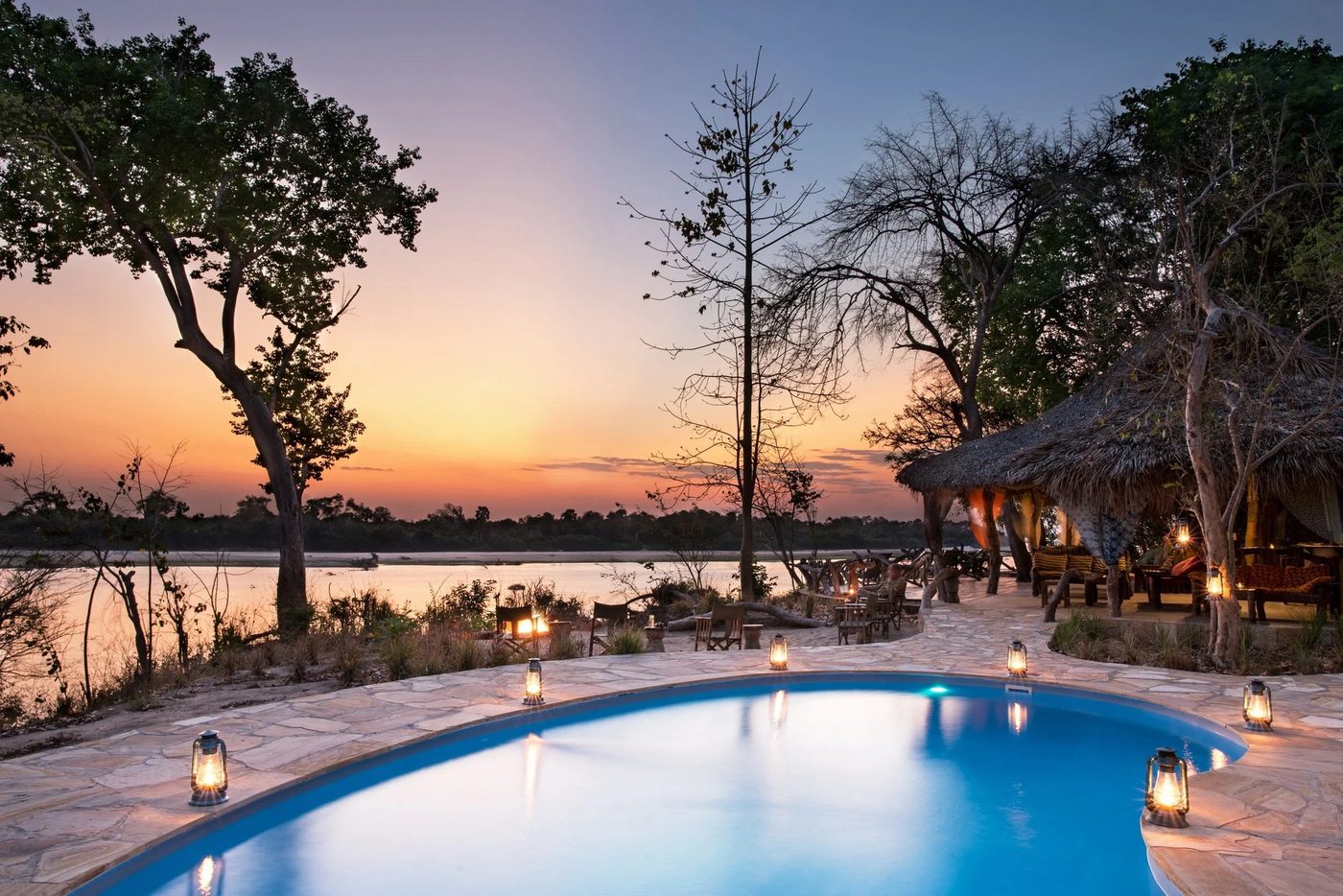 Von Laternen beleuchtete Pooldeck mit Blick auf den Rufiji bei Einbruch der Dunkelheit im Selous River Camp, Nyerere