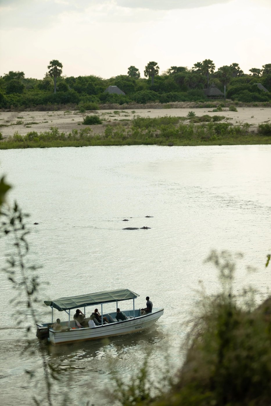 Vue sur la rivière Rufiji avec un bateau qui passe au Selous River Camp