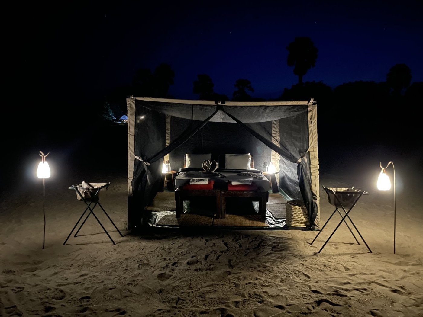 Flugcampbett unter Leinwand nachts beleuchtet nahe Selous Wilderness Camp