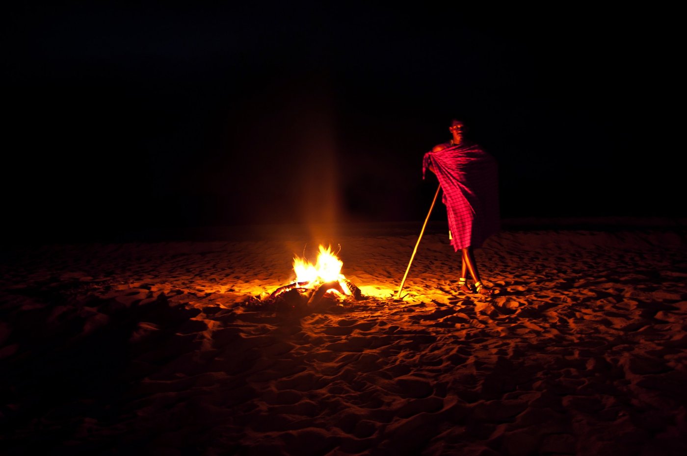 Massai-Tänzer Silhouette vom Lagerfeuer nachts im Selous Wilderness Camp