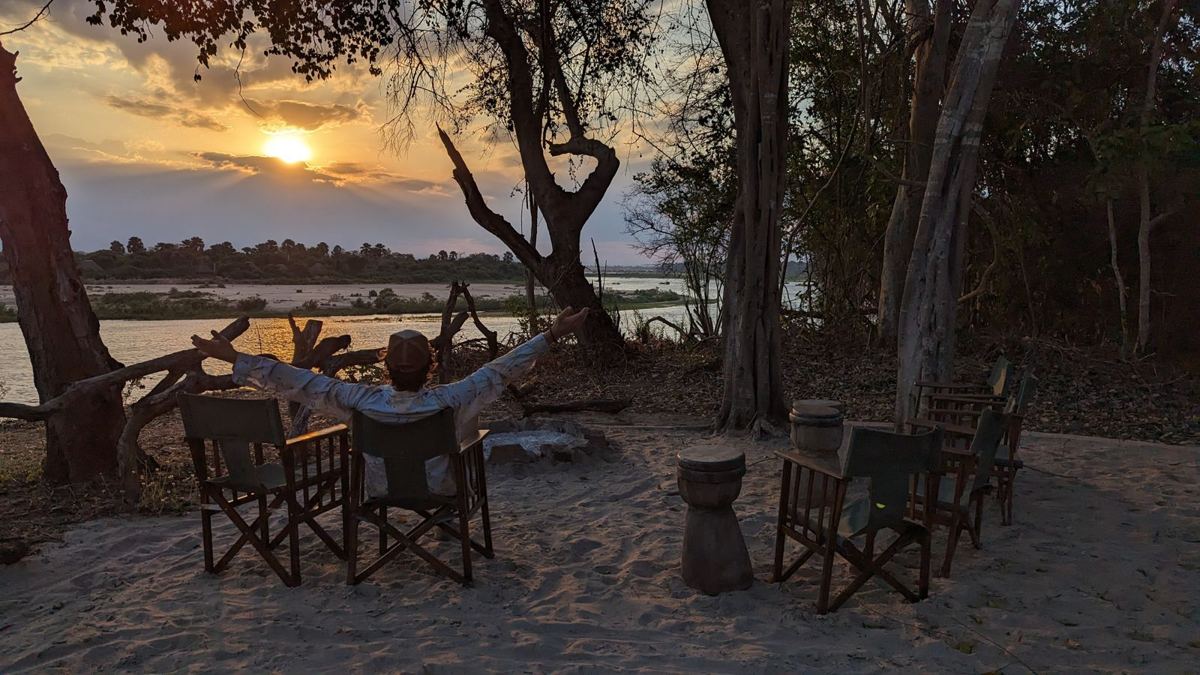 Campstühle auf einem Sandufer über dem Rufiji bei Sonnenuntergang